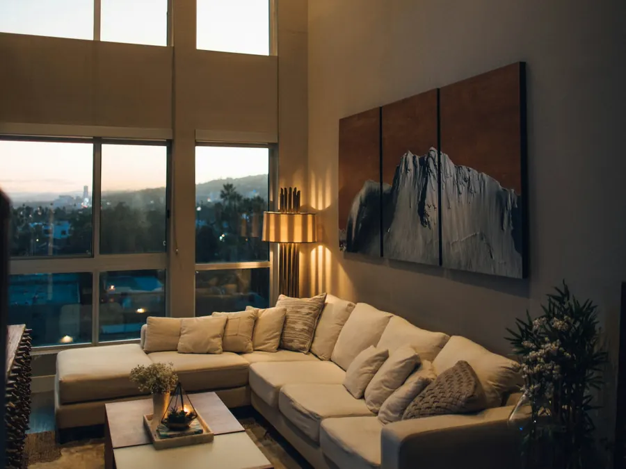 Stylish high-ceiling city apartment with a cream sectional and skyline views at dusk